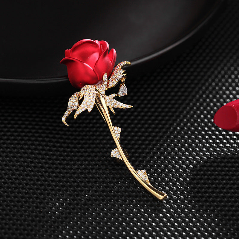 Red enamel rose brooch on black textured fabric