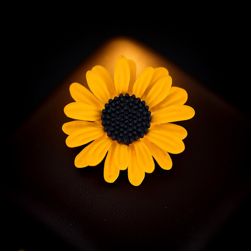 Sunflower enamel brooch on dark background