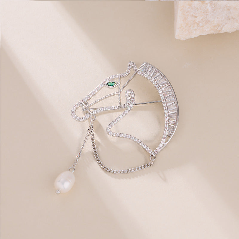 Silver horse brooch flat lay with pearl drop