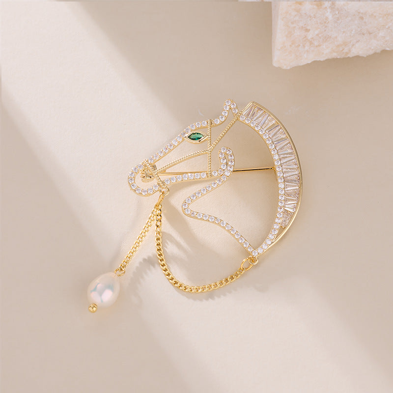 Gold horse brooch flat lay with pearl drop